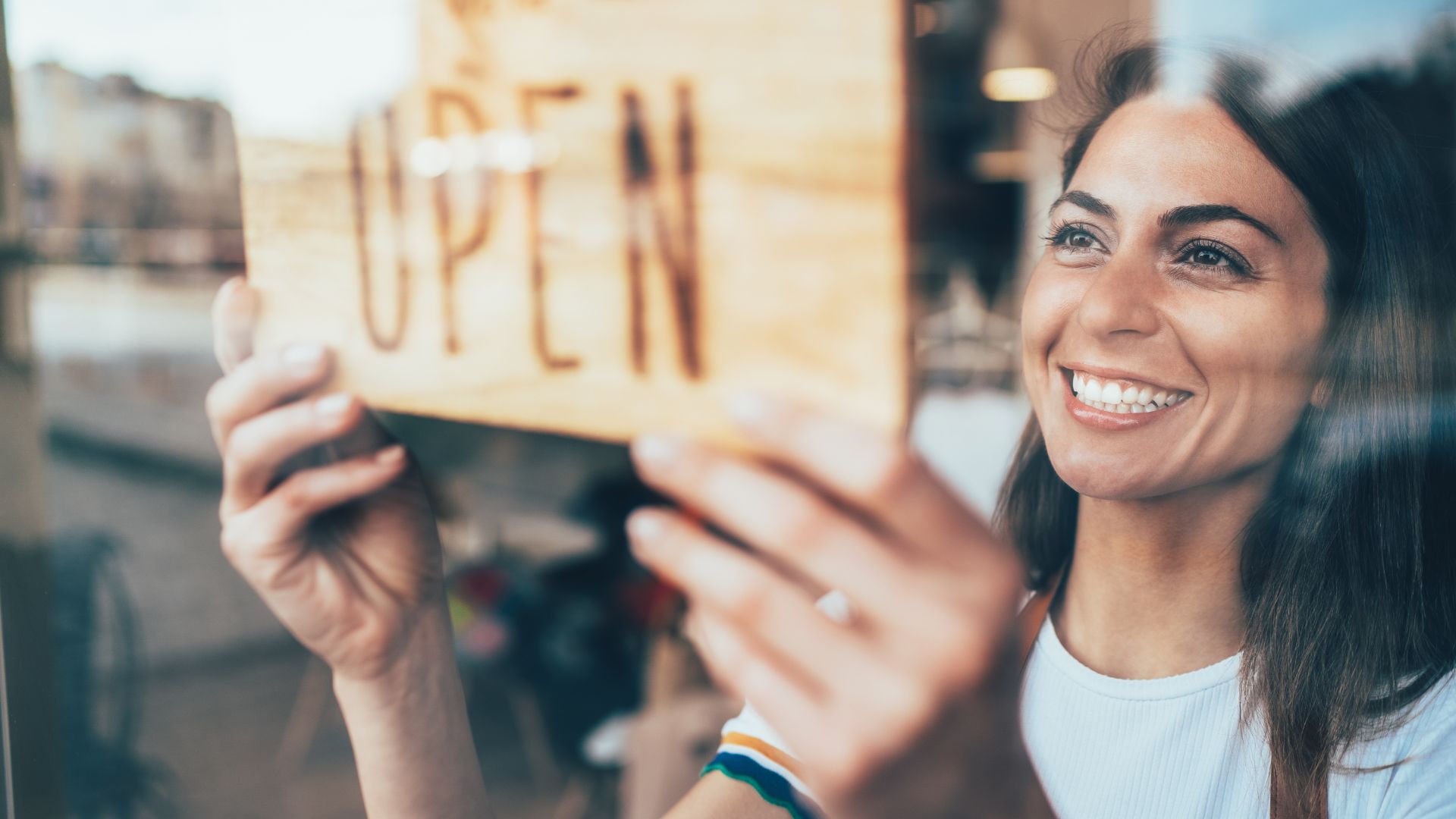 A woman holding up a wooden sign in front of a window