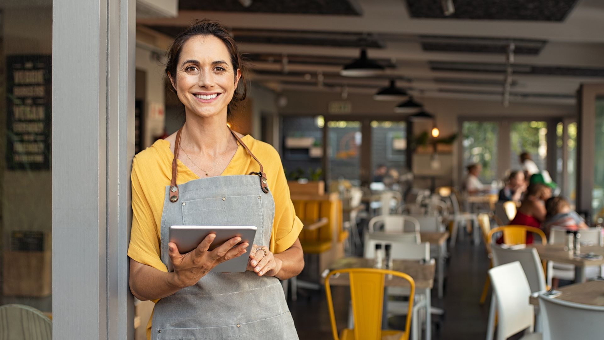 A woman in an apron is holding a tablet