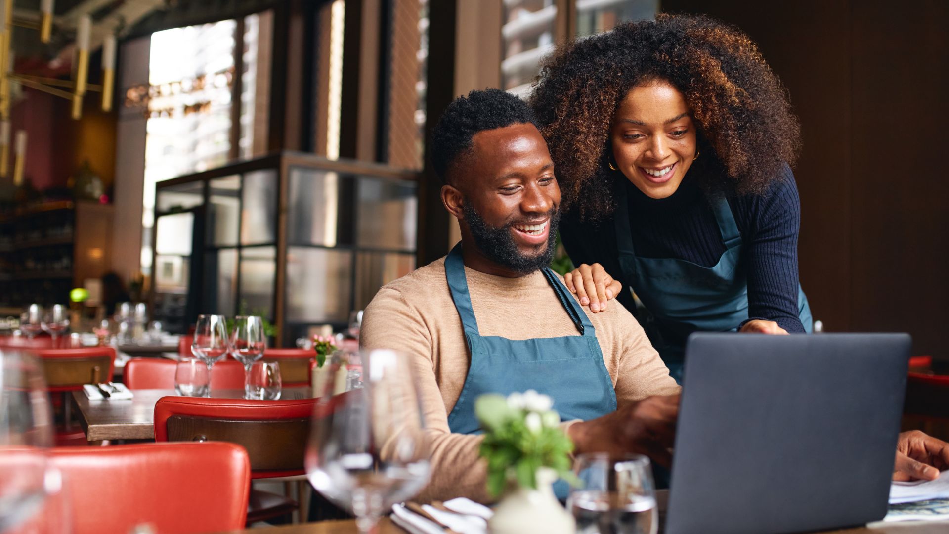 A man and woman sitting at a table with a laptop